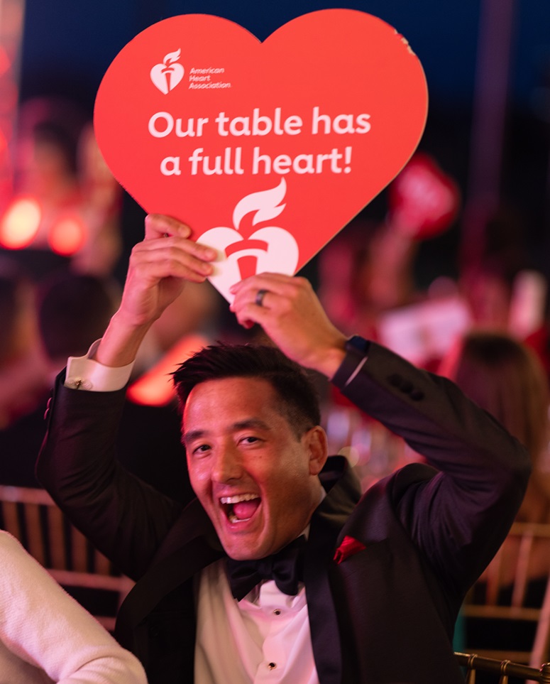 Man holding up a sign reading "Our table has a full heart!".